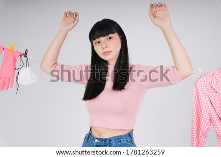 Beautiful asian thai long dark hair woman in pink shirt hanging herself on cloth rack with wet clothes over white background.