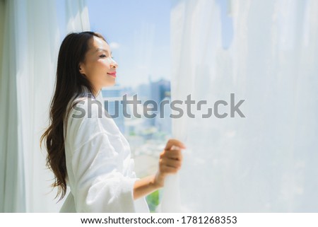 Portrait beautiful young asian woman open curtain window and look outside of window for the view