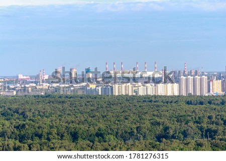 View of thermal power station in Russia among green trees. Smoke rises from several pipes. Theme of fuel and power generation.