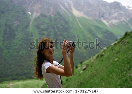 Beautiful woman with camera on background of mountains Alps travel hiking sun fresh air