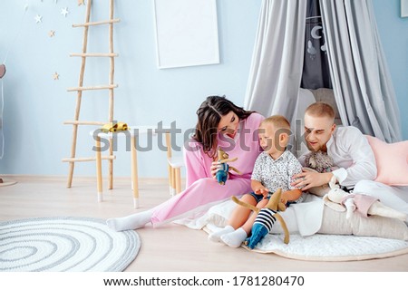 family mother father and little son play together in children's light playroom