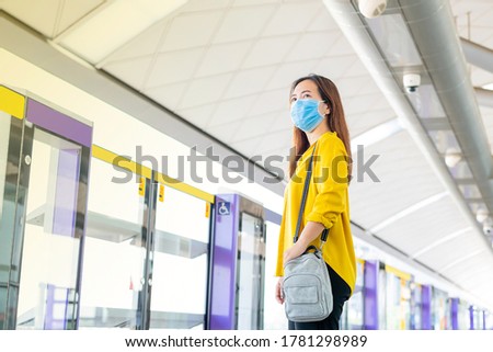 Asian women wearing casual wear and medical mask going to travel on holiday by sky train during covid-19 or corona virus at modern platform of sky train station. Bangkok Thailand. Girl lifestyle.