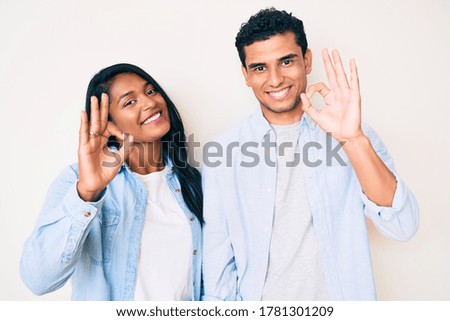 Beautiful latin young couple wearing casual clothes smiling positive doing ok sign with hand and fingers. successful expression. 