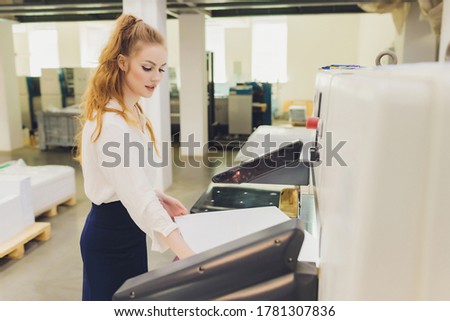 Young woman working in printing factory. Printing Press.