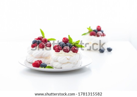 mini Pavlova dessert with raspberries and blueberries with castor sugar on a white background