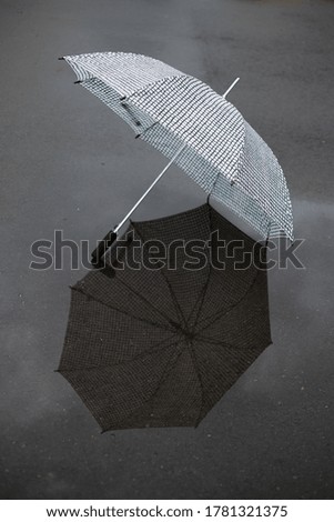 Rainy weather-puddles, wet ground and street, beautiful open umbrella on the ground