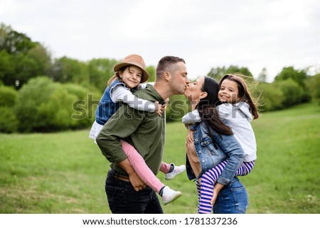 Happy family with two small daughters standing outdoors in spring nature.