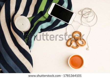 Close up, flat lay, top view. Autumn mood in the office. Warm sweater, orange tea, telephone with headphones. White background. Copy space.