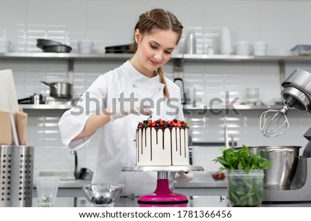 Pastry chef decorates the cake with chocolate levels of berries and mint. Royalty-Free Stock Photo #1781366456