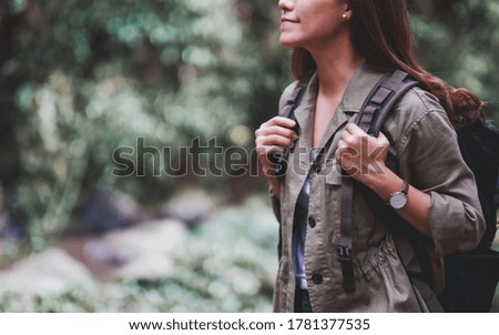 A female traveler with backpack walking  by mountain stream for hiking concept
