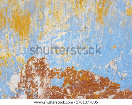 Damaged wall texture. Yellow and blue paint peeling off the red wall.