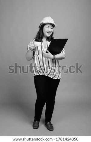 Full body shot of mature beautiful Asian businesswoman as engineer with clipboard