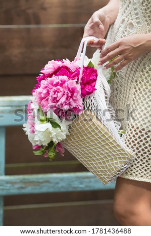 A beautiful bouquet of delicate peonies in the hands of a woman. Close up.The woman inhales the fragrance of flowers. Concept of happy women's day and mother's day celebrations.Copy of the text space.