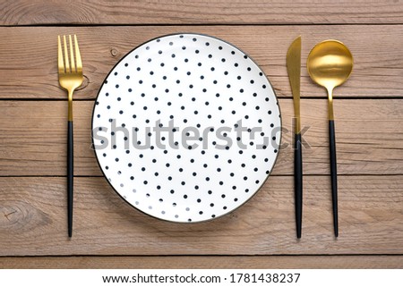 empty white round plate with black peas, fork, knife, spoon on wooden table Top view Flat lay Dishes for breakfast, lunch or dinner Mock up