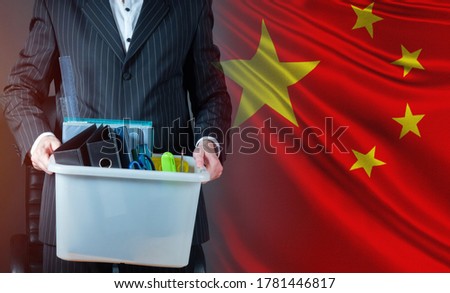 China. Man symbolizes dismissal. Man holds a plastic box in his hands. Man on background of PRC flag. Personal items in box in a person hands. Dismissal employee in China. Dismissal employee company