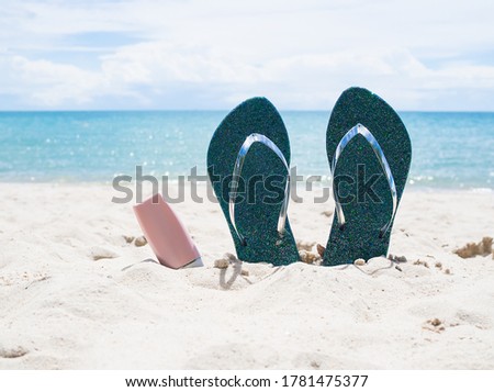 Flip flops and sunsreen protection UV A,UV B. on sand beach and blur image of sea. for contains articles about the sea or travel summer in holidays.