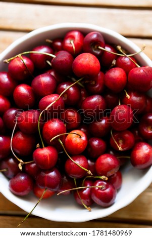 sweet red cherries in a plate on a wooden background Royalty-Free Stock Photo #1781480969