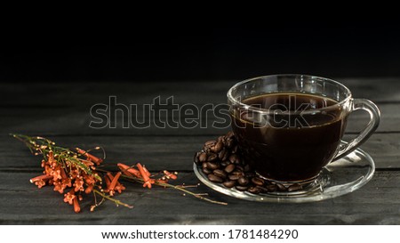 Hot coffee in a coffee cup and roasted coffee beans with a dark tone wood floor. And there is a copy space.