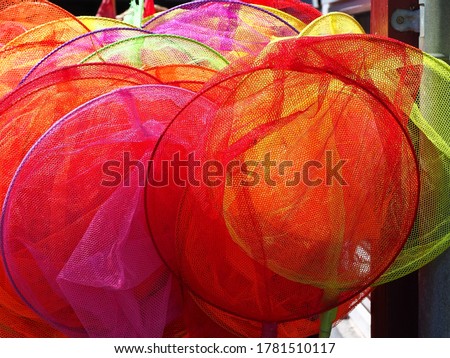 Colorful toy fishing nets on display in a store by the ocean