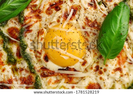 carbonara pizza with tomatoes, pesto, basil, mozzarella, parmesan and egg close up on gray concrete or stone background top view