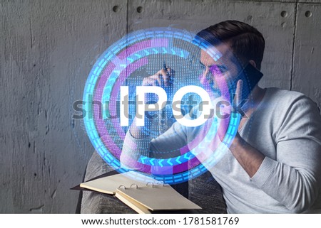 Handsome analyst in casual long sleeve talking phone, taking notes at office workplace try to analyze IPO project. Double exposure. Initial public offering hologram. Royalty-Free Stock Photo #1781581769