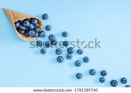 Fresh berries blueberries in waffle cone on pastel blue background. Summer background. Creative berries concept. Flat lay, top view, copy space