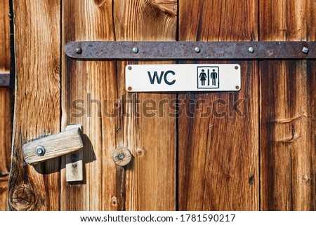Handmade painted toilet wc sign on wooden door of farmhouse