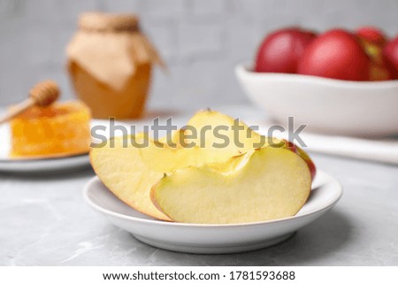 Apple slices near honey on light grey marble table, closeup. Rosh Hashanah holiday