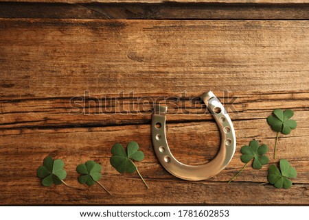 Clover leaves and horseshoe on wooden table, flat lay with space for text. St. Patrick's Day celebration