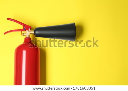 Fire extinguisher on yellow background, top view. Space for text