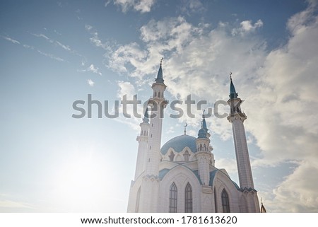 Beautiful mosque with minarets on a blue background sky with white clouds and sun highlights on a sunny day. World Religions - Islam
