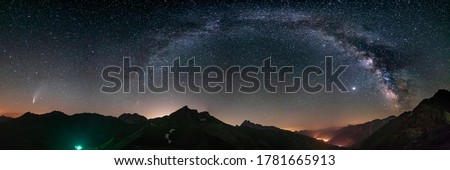 Milky Way arc and stars in night sky over the Alps. Outstanding Comet Neowise glowing at the horizon on the left. Panoramic view, astro photography, stargazing. Royalty-Free Stock Photo #1781665913