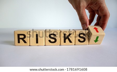 Hand is turning a cube and changes the direction of an arrow symbolizing that the risks is going down or vice versa. Beautiful white background, copy space. Business concept.