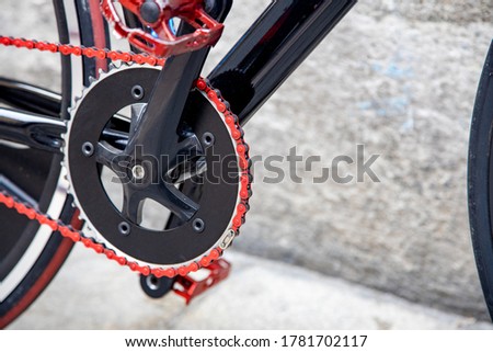 closeup of black bicycle pedal with red chain