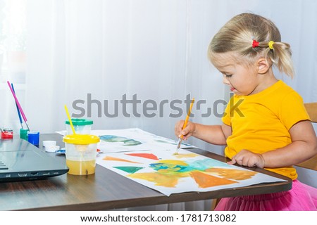 A little girl carefully draws a picture. The child is very interested in creativity at home.