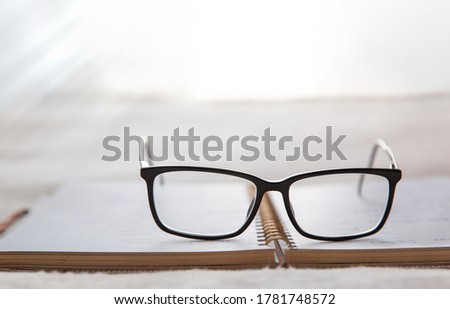 Image of an open notebook placed in bed with glasses at the top and a window in the background.blurred background. High quality photo