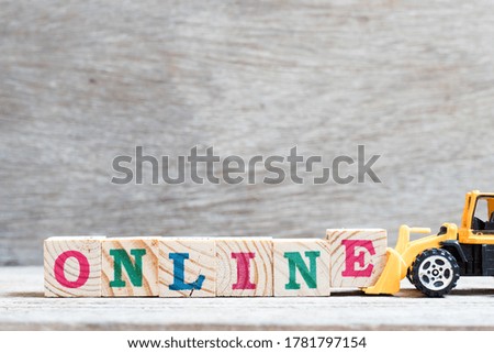 Toy bulldozer hold letter block e to complete word online on wood background