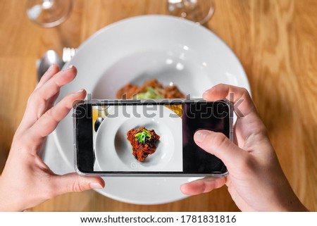 Man hand with smartphone photographing food at restaurant or cafe. High quality photo