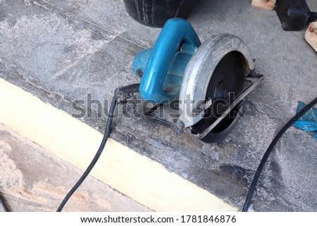 Blue circular saw, electric hand tools, on cement flooring closeup in work area. 