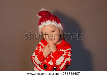 Little girl grimaces in a New Year's hat and a sweater
Merry christmas and happy new year