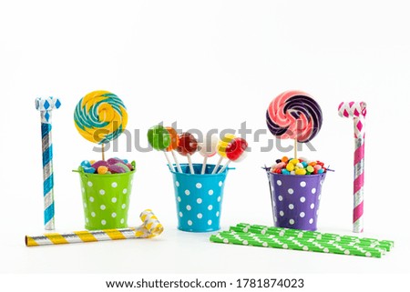 a front view lollipops and candies inside baskets on the white desk color sugar sweet