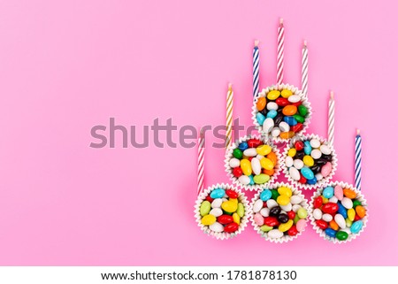 a top view colorful candies along with candles inside bowls on the pink background sweet sugar color