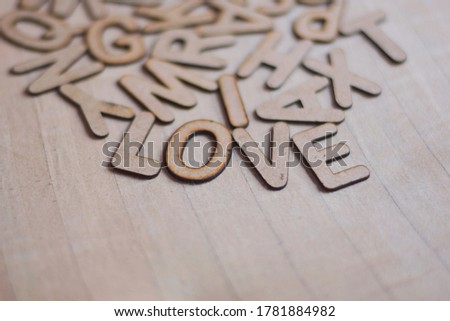 Word says love along with some scattered wooden alphabet letters on beige fabric background. Selective focus, concept.