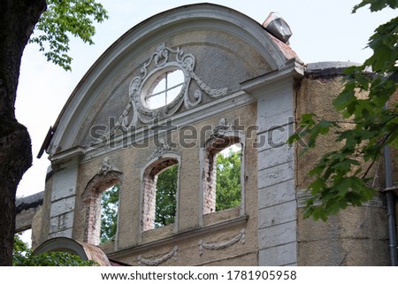 Facade with stucco molding and an oval window of a destroyed building