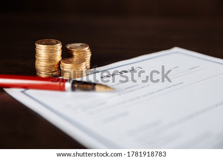Signing a contract, pen and coins on a wooden table