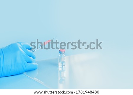 Syringe in a hand of a doctor or nurse and medicine or vaccine vial. Vaccination and immunization concept. Medicine and health care. Vaccine trials and research. Pharmacy. COpy space
