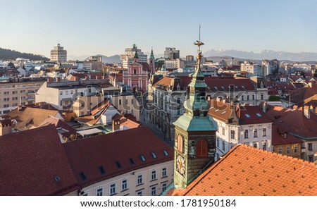 Scenic panoramic aerial drone view of rooftops of medieval city center, town hall and cathedral church in Ljubljana, capital of Slovenia, at sunset.
