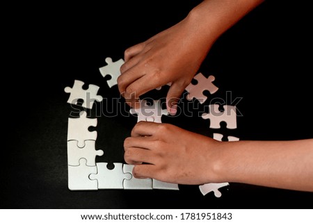 The hand that picked up the white puzzle piece On a black background, work concepts and planning