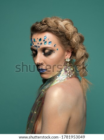 Young woman with fashion makeup on green background