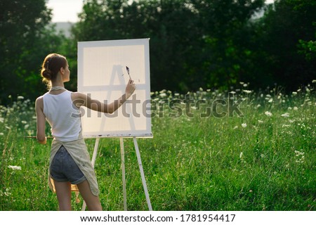 The artist paints a picture outdoors in the meadow and sunlight